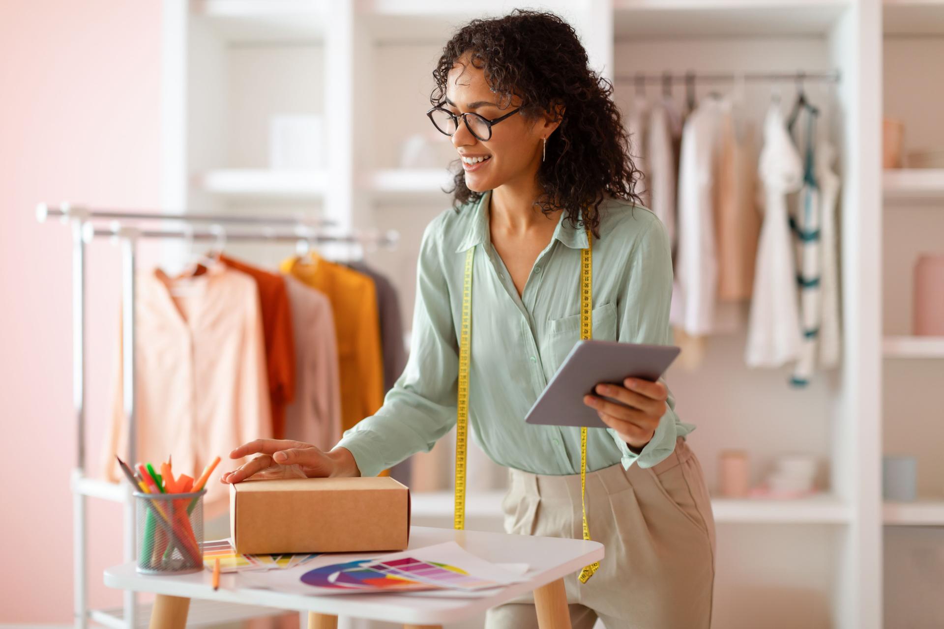 Smiling latin female fashion designer with tablet and package